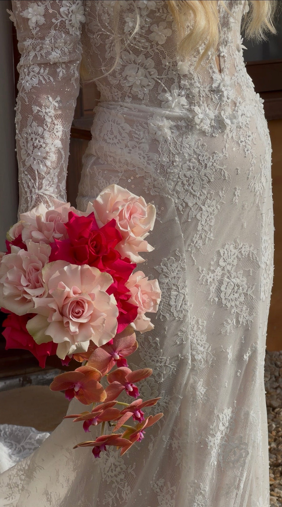 Close-up of a wedding dress with a bouquet of flowers held by a bride.
