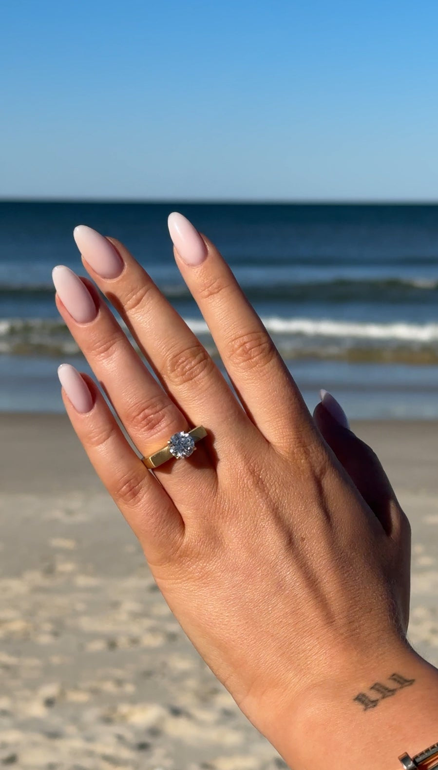 Hand with a ring on a beach. Wedding content creation for a beach proposal 